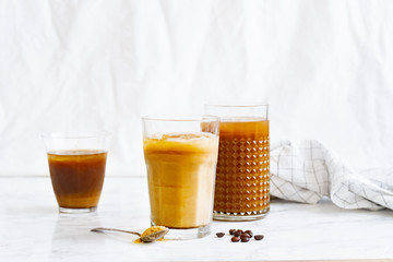 Iced coffee with cream and vanilla in various glasses on white background. Summer cocktail or dessert