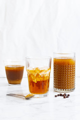 Iced coffee with cream and vanilla in various glasses on white background. Summer cocktail or dessert