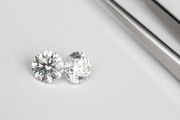 Carat size diamonds compared with tweezers on white isolated
