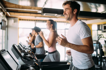 Fototapeta na wymiar Group of young people running on treadmills in modern sport gym