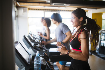 Young people running on a treadmill in health club.