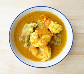 Kangsom- Thai sour soup with shrimps and fried eggs with climbing wattle, A Thai sour soup in Top down view on a wooden board
