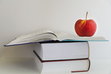 Back to school. Red apple next to books on a white background