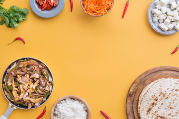 Fajitas and ingredients top view and yellow background