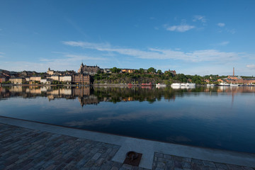 Fototapeta premium Boats, pier and landmarks in Stockholm a tranquil morning, 