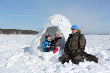 Fototapeta na wymiar Happy grandfather, grandmother and grandson sitting near the snow on a snowy glade in winter