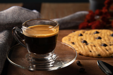 A cup of hot coffee espresso  with coffee bean and homemade cookie on wooden table