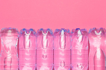 Plastic bottles with pure water on pink background top view space for text