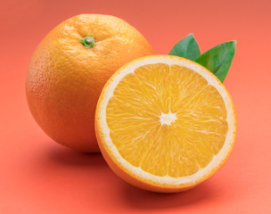 Orange fruit with orange slices and leaves isolated on orange background.