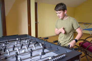 Happy boy playing table soccer in room of the house. Sports entertaining games.