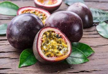 Passion fruits and its cross section with pulpy juice filled with seeds. Wooden background.