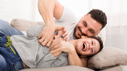 Young dad have fun tickling his laughing son