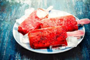 Fruit ice cream from strawberry, fruit ice on a stick,popsicle, lying on a plate on blue wooden vintage background