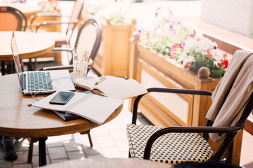 Laptop, smartphone, earpods, notebooks and pen on a cafe table