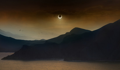 Total solar eclipse in dark red sky above sea and mountains