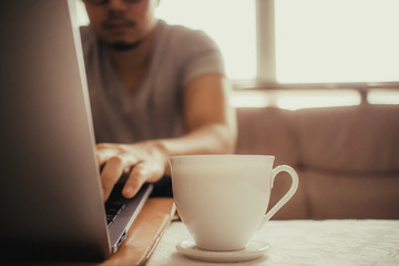 White cup of hot coffee on the table of a freelance man.
