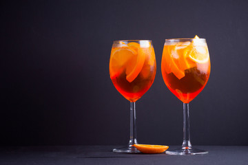 Cocktail aperol spritz on black background. Summer alcohol cocktail with orange fruit and fresh mint. Italian cocktail aperol spritz on wooden boards