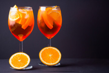 Cocktail aperol spritz on black background. Summer alcohol cocktail with orange fruit and fresh mint. Italian cocktail aperol spritz on wooden boards
