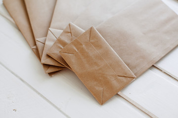 Paper bags on light wooden floor. Simple brown paper bags for lunch or meal. The layout for the design. Environmental ship packages.