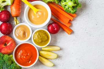 Vegetable and fruit baby puree in white bowls with ingredients, top view. Baby food concept.