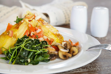 Spanish Potato Tortilla served with mushrooms and spinach, casual dining restaurant food	