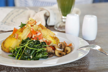 Spanish Potato Tortilla served with mushrooms and spinach, casual dining restaurant food	