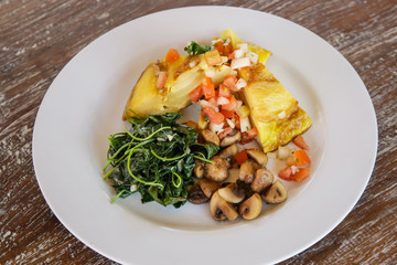 Spanish Potato Tortilla served with mushrooms and spinach, casual dining restaurant food	