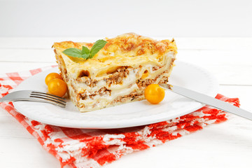 Closeup portion of homemade lasagna on white wooden table. Mediterranean italian food.