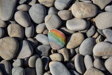 Closeup of rainbow painting on stone pebble on pebble sea beach