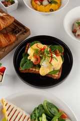 Grilled italian sandwich on wheat toast with greens, benedict egg, chili pepper and cherry tomatoes as a part of breakfast menu