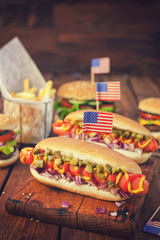 American hot dog with pickles,onions, ketchup, mustard and french fries at a picnic for fourth of...