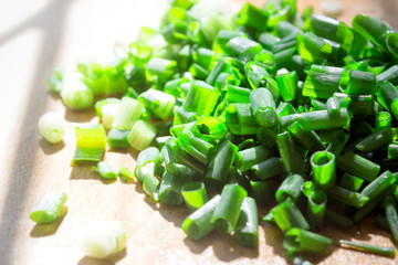 Finely chopped young green onions, on a wooden Board, the morning bright sun.