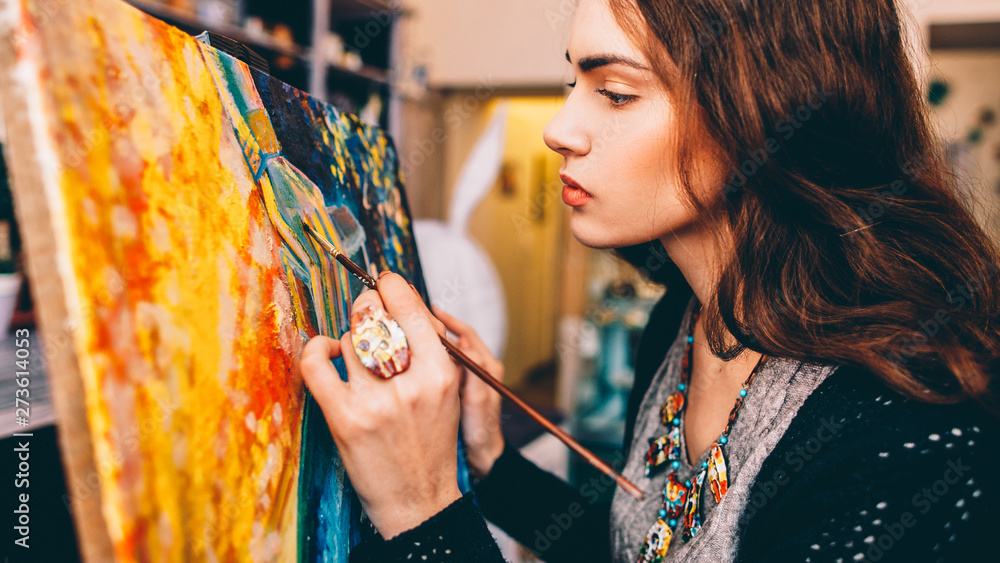 Wall mural art school class. side view of lefthanded female painter creating colorful abstract artwork in studi