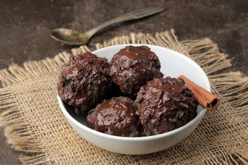 Chocolate ice cream with liquid chocolate with a cinnamon stick and coffee beans on a dark background.