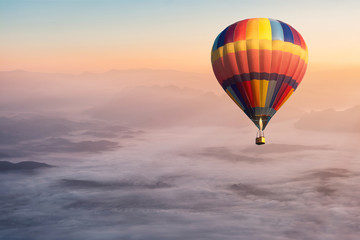 Fototapeta premium Colorful hot air balloon flying in the air with fog and scenery mountains