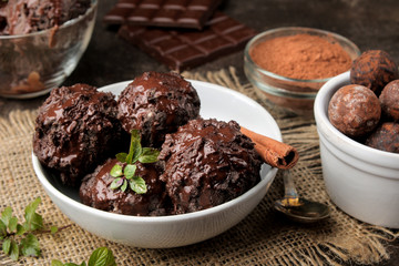 Chocolate ice cream with liquid chocolate with a cinnamon stick and coffee beans on a dark background.