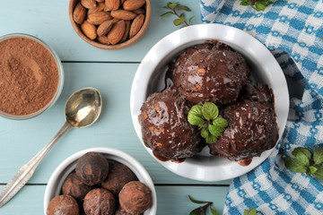 Chocolate ice cream with liquid chocolate and cinnamon sticks on a light concrete background.