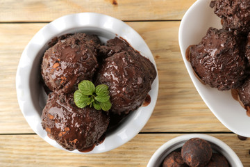 Chocolate ice cream with liquid chocolate and cinnamon sticks on a light concrete background.