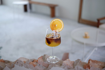 A refreshing wine glass of iced coffee mixed with fresh orange juice on blur background. selective...