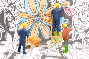 Macro shot on miniature figures as painters working on colouring details on a wallpaper