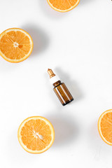 Citrus essential oil, vitamin c serum with fresh juicy orange fruit on white background. High dose vitamin c synthetic for skin. Flat lay, top view, copy space
