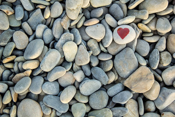 Fototapeta na wymiar stone heart painted with a red paint marker on the pebble as a gift for Saint Valentine day on the pebble background.