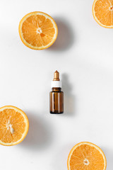 Bottle citrus essential oil and fresh juicy orange fruit on white background. High dose vitamin c...