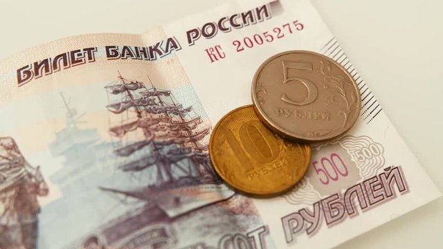 Extreme close up panning shot of Russian ruble currency lying on the table - 500 rubles in paper, and 10 and 5 in coins.