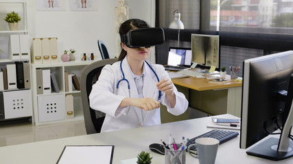 asian female doctor wear virtual reality goggles in hospital. Medical technology research institute and nurse staff service concept. young girl worker intern in clinic office with headset vr glasses