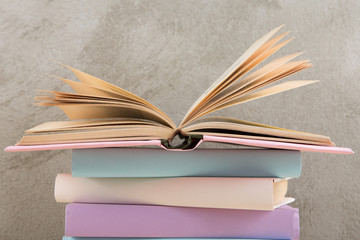 Education and reading concept - group of colorful books on the wooden table, concrete wall blackboard