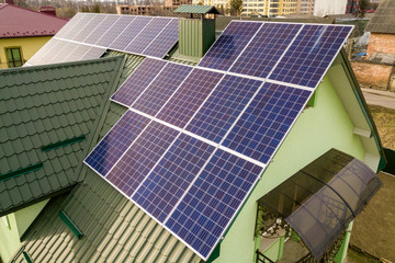 Aerial view of  house cottage with blue shiny solar photo voltaic panels system on the roof....