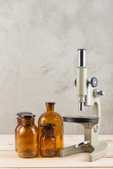 Obraz na płótnie Canvas Vintage pharmaceutical bottles, microscope on the wooden desk - retro pharmacy