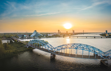 Fototapeta na wymiar Panoramic view over Riga city at sunset. Iconic railroad bridge and old town panorama. Picturesque scenery of historical architecture. National library of Latvia. 