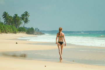 Fototapeta na wymiar The girl is walking along the beach